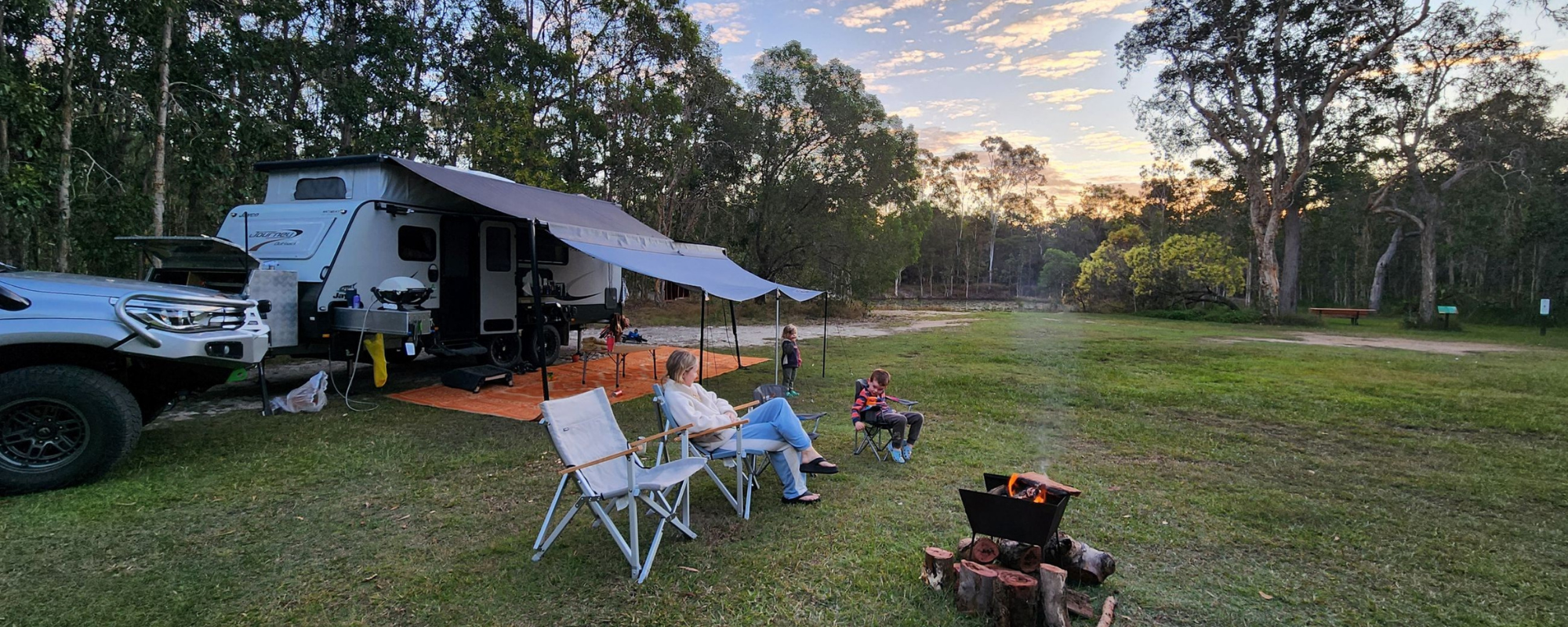 Traveller's Rest 1770 Eco Camping family camped by fire with caravan and awning
