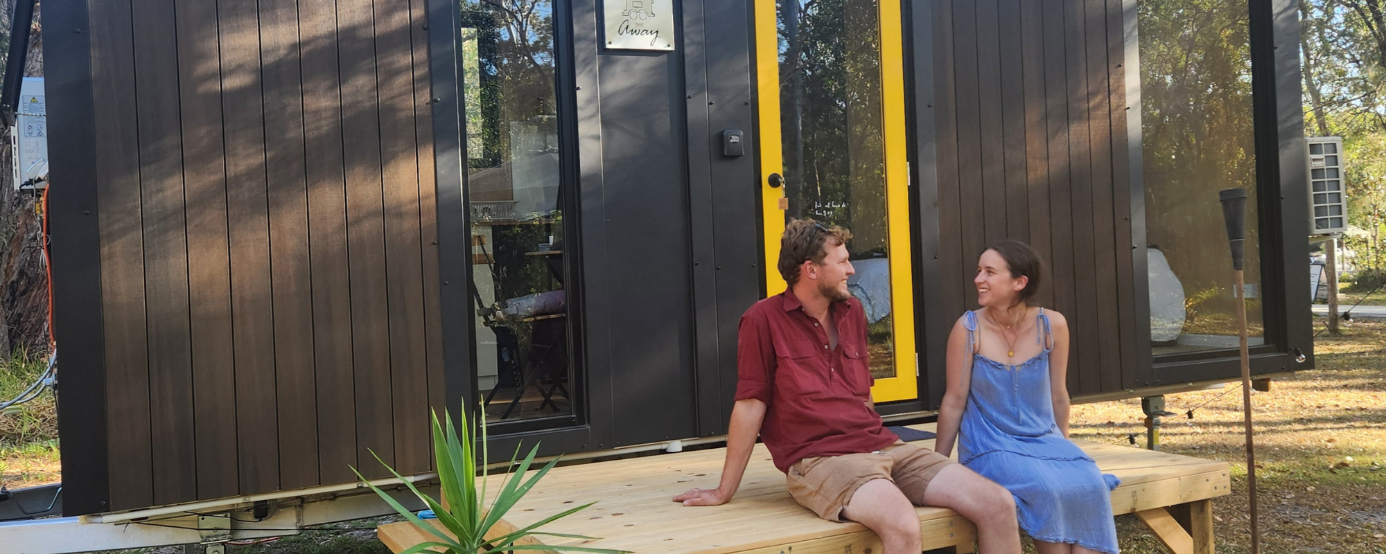 Traveller's Rest 1770 Eco Camping couple sitting out the front of a tiny home