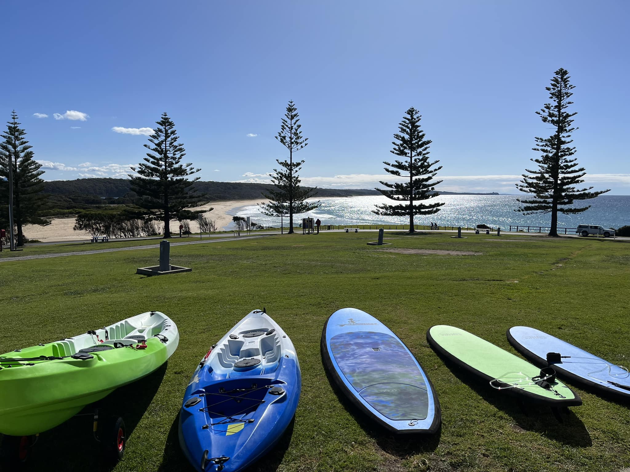 dalmeny campground surf boards and paddle boards in foreground with grassed area overlooking coastal view of beach and sea