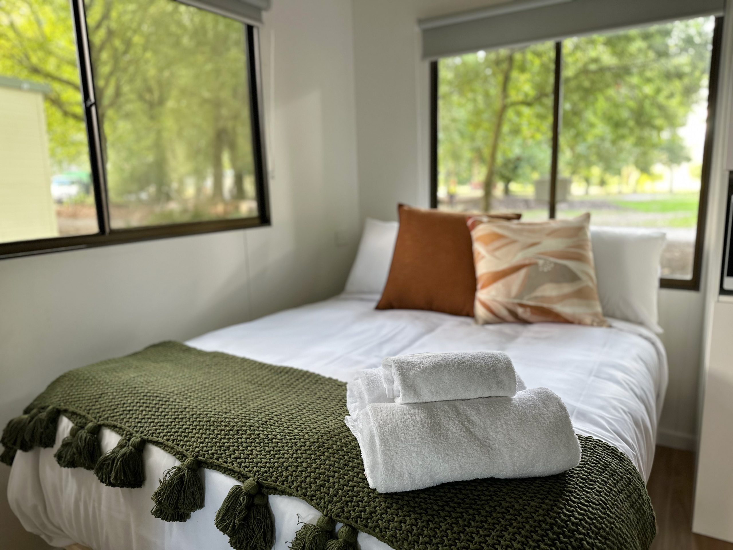 tawonga tourist park bedroom of cabin with windows showing trees and nature outside