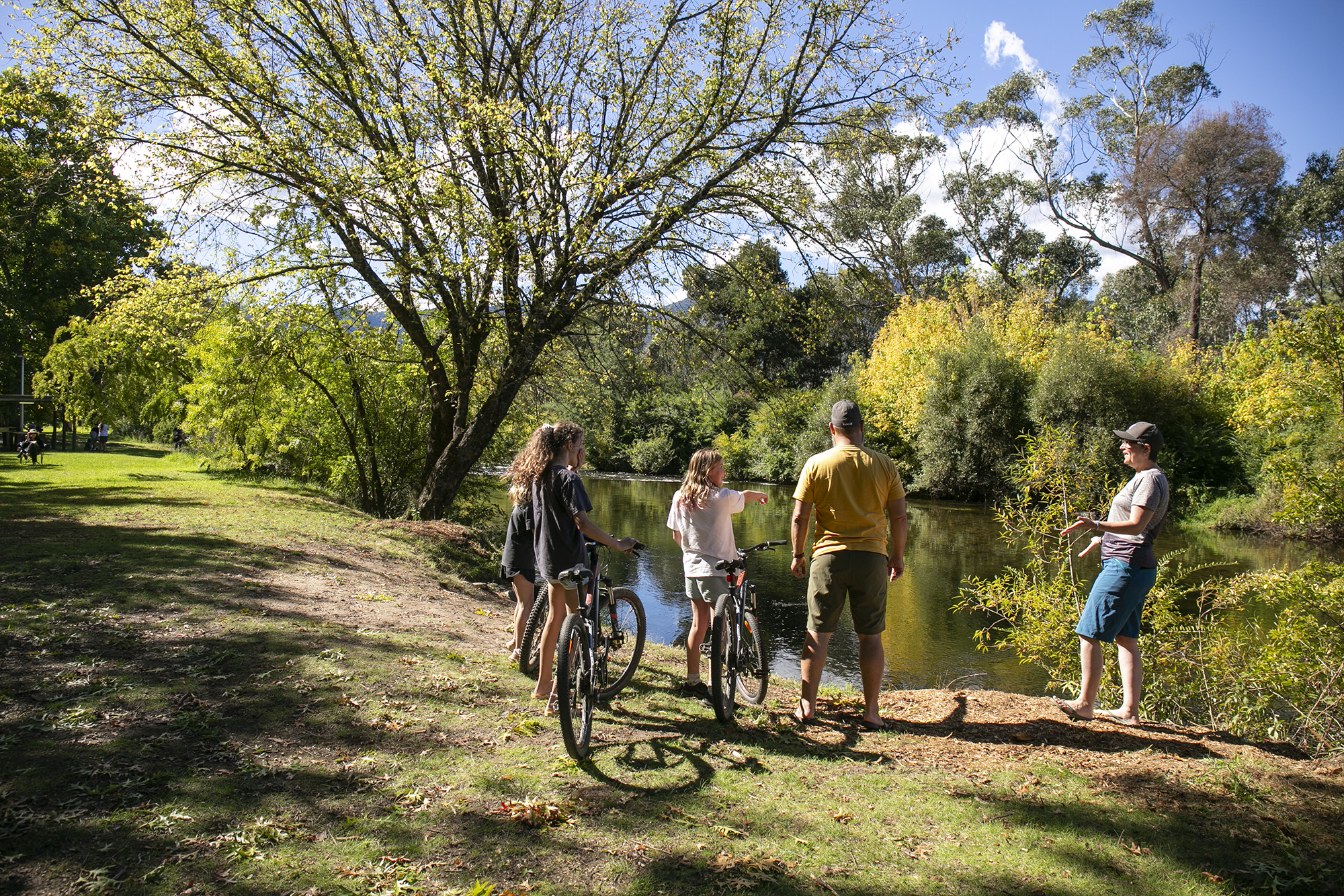 tawonga tourist park family bike riding next to river in the sunshine