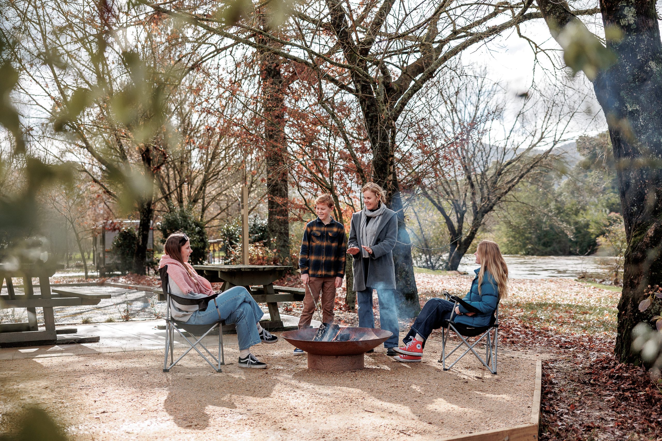 tawonga tourist park family sitting around a campfire with the river in the background