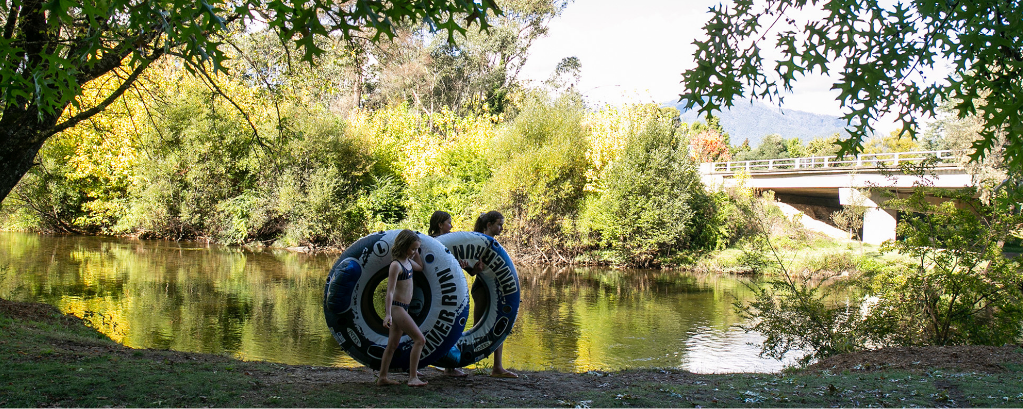 tawonga tourist park river with children carrying inflatable tires to go swimming